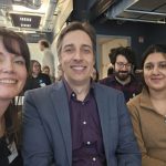 three people sitting in row and smiling,(left to right: one woman,man,woman) selfie clicked